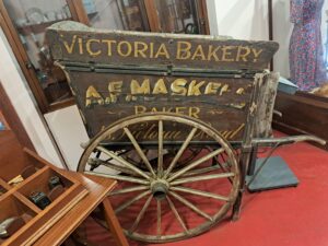 A hand held bakers cart with the words 'Victoria Bakery' painted on the side.