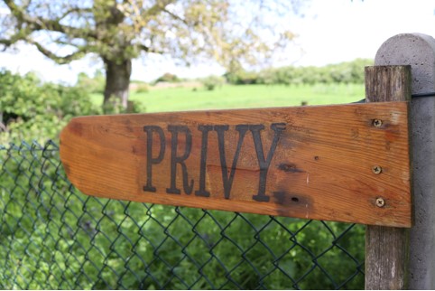 Wooden sign pointing to a privy