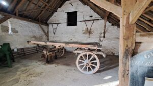 Image of a flatbed wagon with a missing wheel in an old stone barn