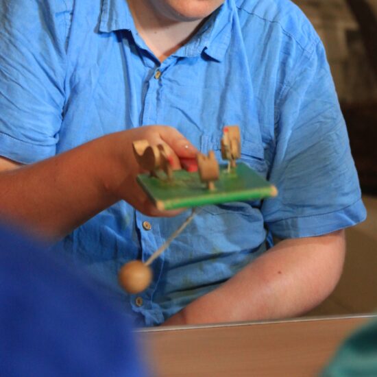 A male playing with a pecking chickens game. The ball is swinging in motion.