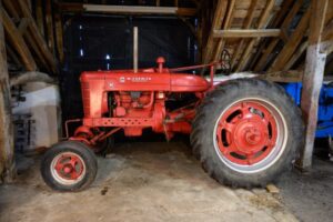 McCormick Red Tractor seen from the side. It has a small wheel at the front and a large one at back.