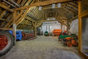 Displays of historic agricultural machinery in a wooden beamed farm barn.