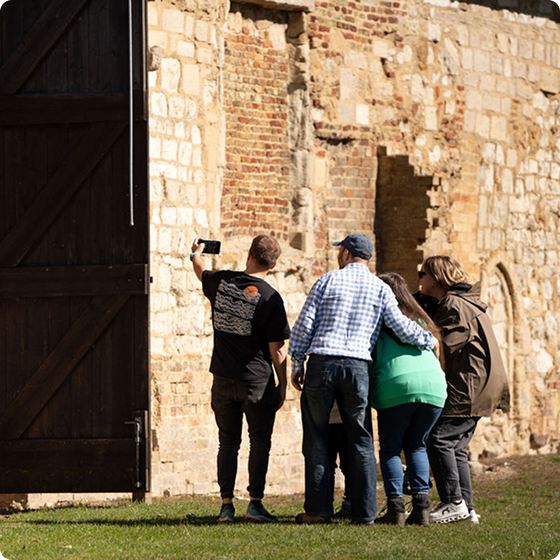 A group of four people taking a selfie outside an old barn.