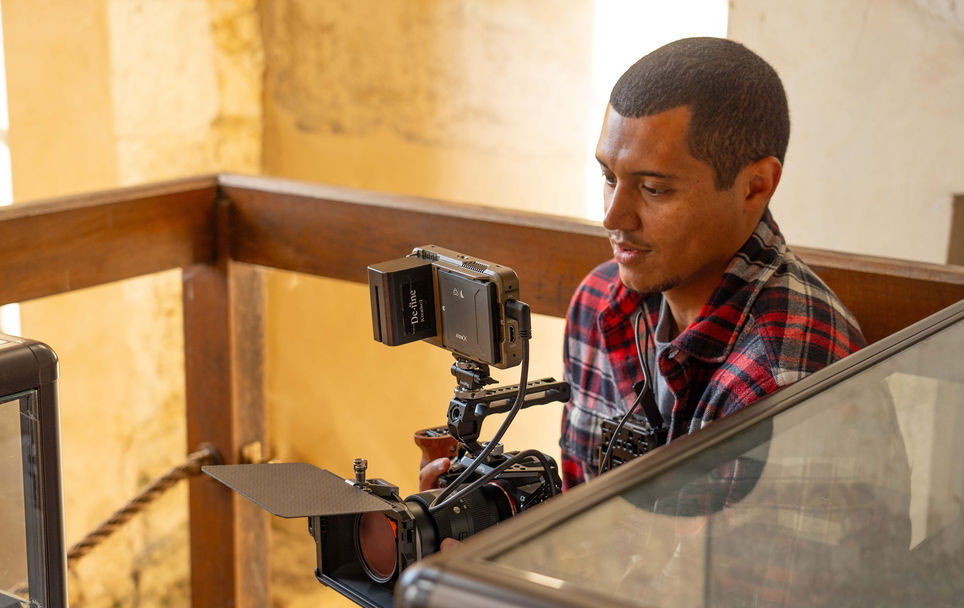 Man with video camera next to museum display cases